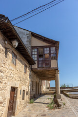 Cobblestone street with picturesque stone residential buildings and flowered balconies in Puebla de Sanabría, Zamora province, Castilla y León, Spain.