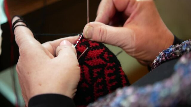 close-up of knitting woolen socks in the traditional way, hand knitting woolen socks with traditional ornaments, close-up of woman's hands with needles that knitting socks, serbian woolen socks