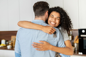 Delighted pleasant young African American woman hugging her boyfriend and feeling thankful for...