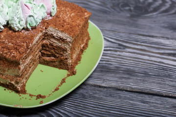 Honey cake decorated with zephyr tulips. The piece is cut off. On pine boards.