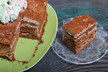 Honey cake decorated with zephyr tulips. The piece is cut off. On pine boards.