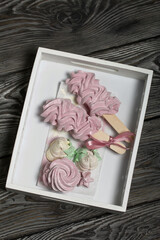 Homemade marshmallow on a stick. Lies in a white tray on pine boards.