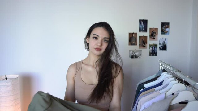 Happy Young  Woman Is looking in a mirror at herself
Thinking What to Wear Putting on T-shirt
