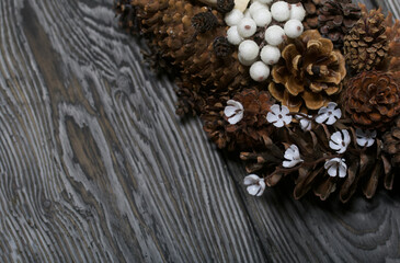A wreath of cones, wine corks and decorative elements. Lies on pine boards. Close-up shot.