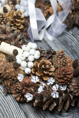 A wreath of cones, wine corks and decorative elements. Lies on pine boards.