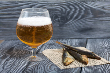 Beer in a glass and smoked fish. On pine boards. A day without diets.