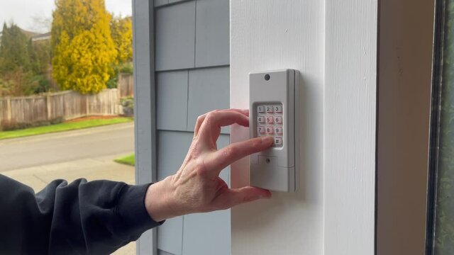 Male finger entering security code on keypad to open or close garage door of home in 4K format