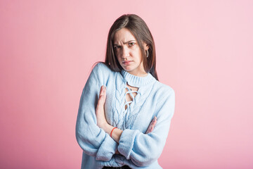 Angry emotions of a brunette girl in the studio on a pink background