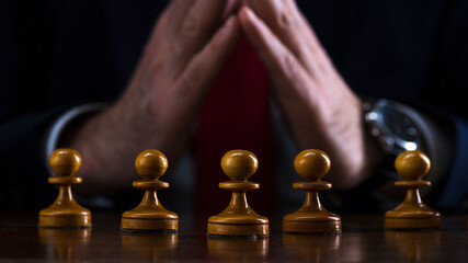 concept of strategy and business planning, businessman at the chessboard in front of lined up white pawns, strategy and tactics, readiness for battle, start of the battle