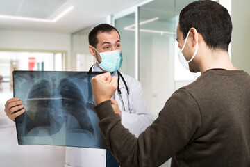 Doctor showing a radiography to an happy patient, covid cure concept