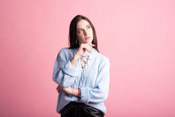 Thoughtful brunette girl in studio on pink background