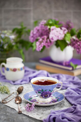 Obraz na płótnie Canvas Purple cup of tae and lilac on gray background