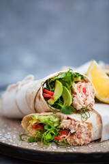 Fresh and healthy wrapped tortilla with crab salad, cucumber, avocado, pepper and green herbs