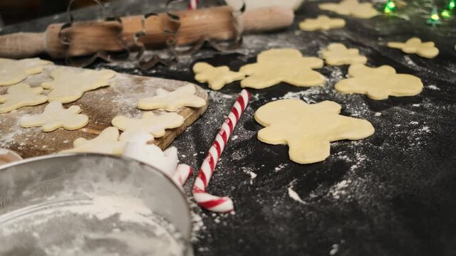 Close up view of gingerbread dought cutted in form of men lying on table sprinkled with flour