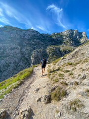 Fototapeta na wymiar Hiker hike the Cares Route in the heart of Picos de Europa National Park, Cain-Poncebos, Spain. Narrow and impressive canyon between cliffs, caves and footpaths.