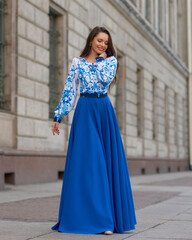 Elegant caucasian woman with long straight brunette hair in blue and white stylish colorful dress...