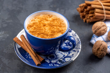 Blue cup of salep milky hot drink of Turkey with cinnamon powder and sticks healthy spice rustic vintage wooden table.