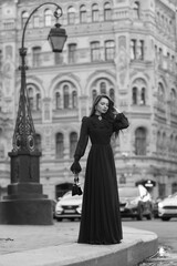 Naklejka premium Elegant caucasian woman with long straight brunette hair in blue and white stylish colorful dress walking city street on a bright day