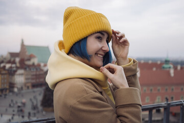 Happy young woman portrait with colored blue hair in coat in front of old town and Christmas tree