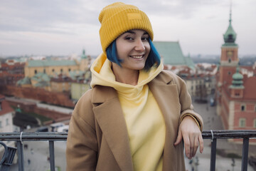 Happy young woman portrait with colored blue hair in coat in front of old town and Christmas tree