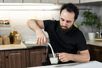 Man pours fresh milk glass from home in the kitchen Breakfast happy family, father with food