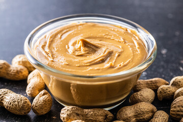 Peanut butter in bowl and peanuts