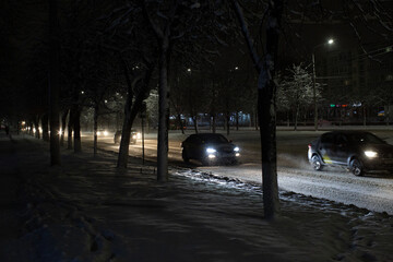 cars at night go along a snowy track