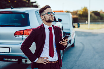 Elegant middle age business man waiting for towing service for help on the road. Roadside...