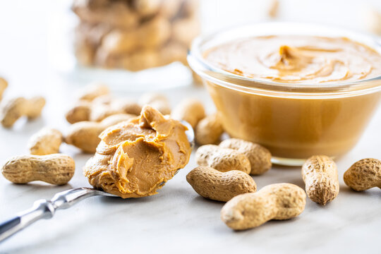 Peanut butter in bowl and peanuts