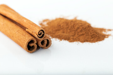 Cinnamon sticks and heap of cinnamon powder on white backround.