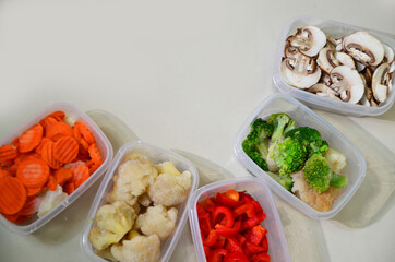 Trays with raw vegetables for freezing. Stocking up for winter storage in plastic containers, puts in a box to freeze red bell peppers, broccoli, cauliflower, carrots