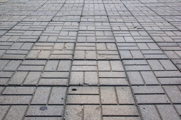 The sidewalk is paved with square decorative tiles.