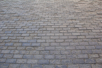 The sidewalk is paved with square decorative tiles.