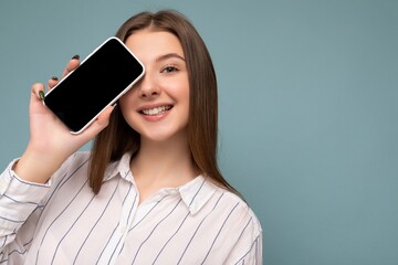 closeup Photo of beautiful smiling young woman good looking wearing casual stylish outfit standing isolated on background with copy space holding smartphone showing phone in hand with empty screen