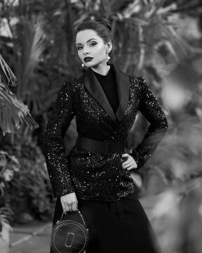 Woman In Black Sequin Blazer Posing Against Exotic Trees On Background