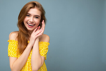 Laughing smiling young beautiful dark blonde woman with sincere emotions isolated on background wall with copy space wearing stylish summer yellow dress. Positive concept
