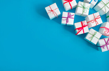 White boxes with colored ribbons lie on a blue background. Top view. Space for the text.