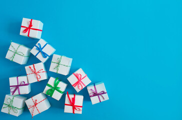 White boxes with colored ribbons lie on a blue background. Top view. Space for the text.