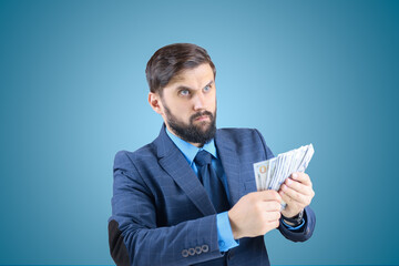 a man in a business suit holds dollar bills in his hand and looks straight, a businessman with banknotes in his hands