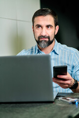 white man with beard working on laptop and looking up