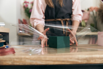 Professional florist young woman is doing bouquets at flower shop