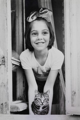 Portrait of soviet girl with tabby cat looking out of window. Early 1980s. Old surface, soft focus....