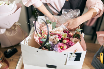 Professional florist young woman is doing bouquets at flower shop