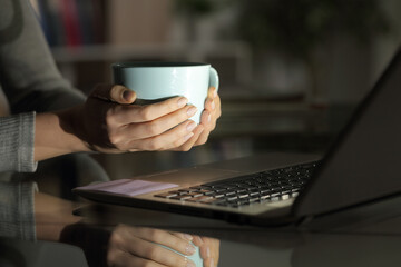 Woman hands holding coffee watching media on laptop