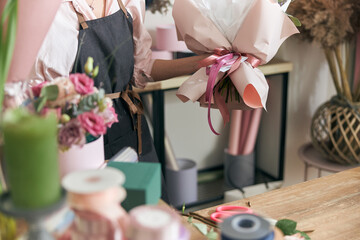 Professional florist young woman is doing bouquets at flower shop