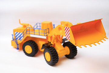 Scale model of a yellow single-bucket loader on white background