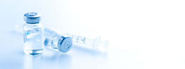 Medical syringe with a needle and a bollte with vaccine.