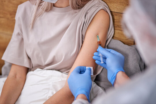 cropped doctor with syringe doing injection vaccine to young female patient, flu,influenza in the shoulder of young woman, nurse injecting,vaccinating people. close-up photo
