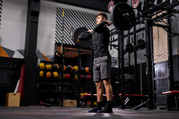 Fototapeta premium fit man lifting barbell in crossfit gym, bodybuilding and weightlifting concept. male in sportswear engaged in cross fit workout, training alone