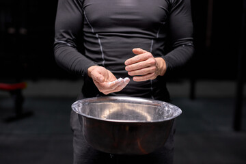 athlete man getting ready for weight lifting training, using talc, preparing hands for workout. at gym. sport and bodybuilding concept